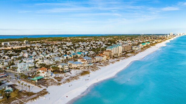 An aerial view of a coastal town with beachfront properties, a sandy beach, and a clear blue ocean. - Ocean Breeze by Southern Vacation Rentals (Destin)