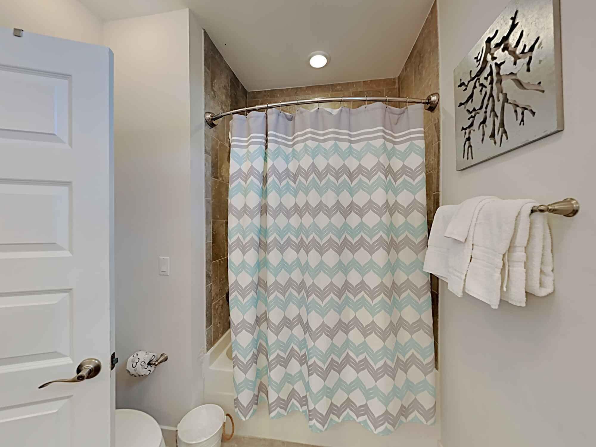 A bathroom with a shower curtain, a towel rack, and a toilet.