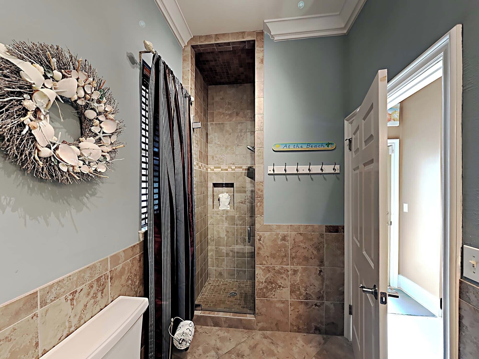 Une salle de bain avec une douche, un porte-serviettes et une couronne décorative.