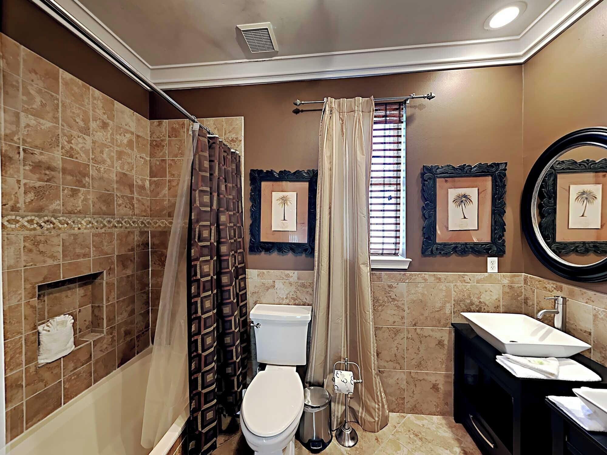 Een badkamer met douche, toilet, wastafel en decoratieve spiegels.
