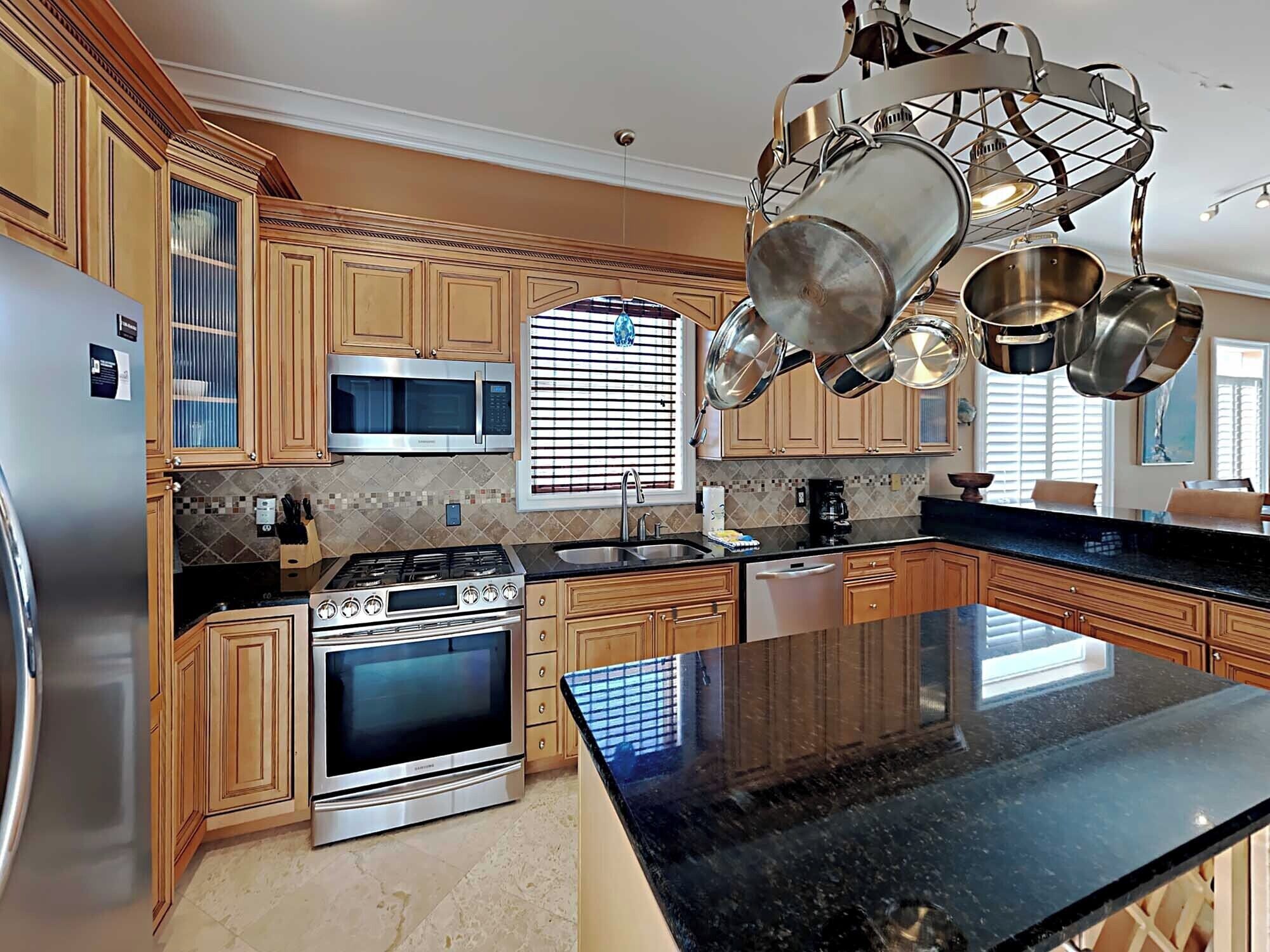 A modern kitchen with wooden cabinets, stainless steel appliances, and a black granite countertop.