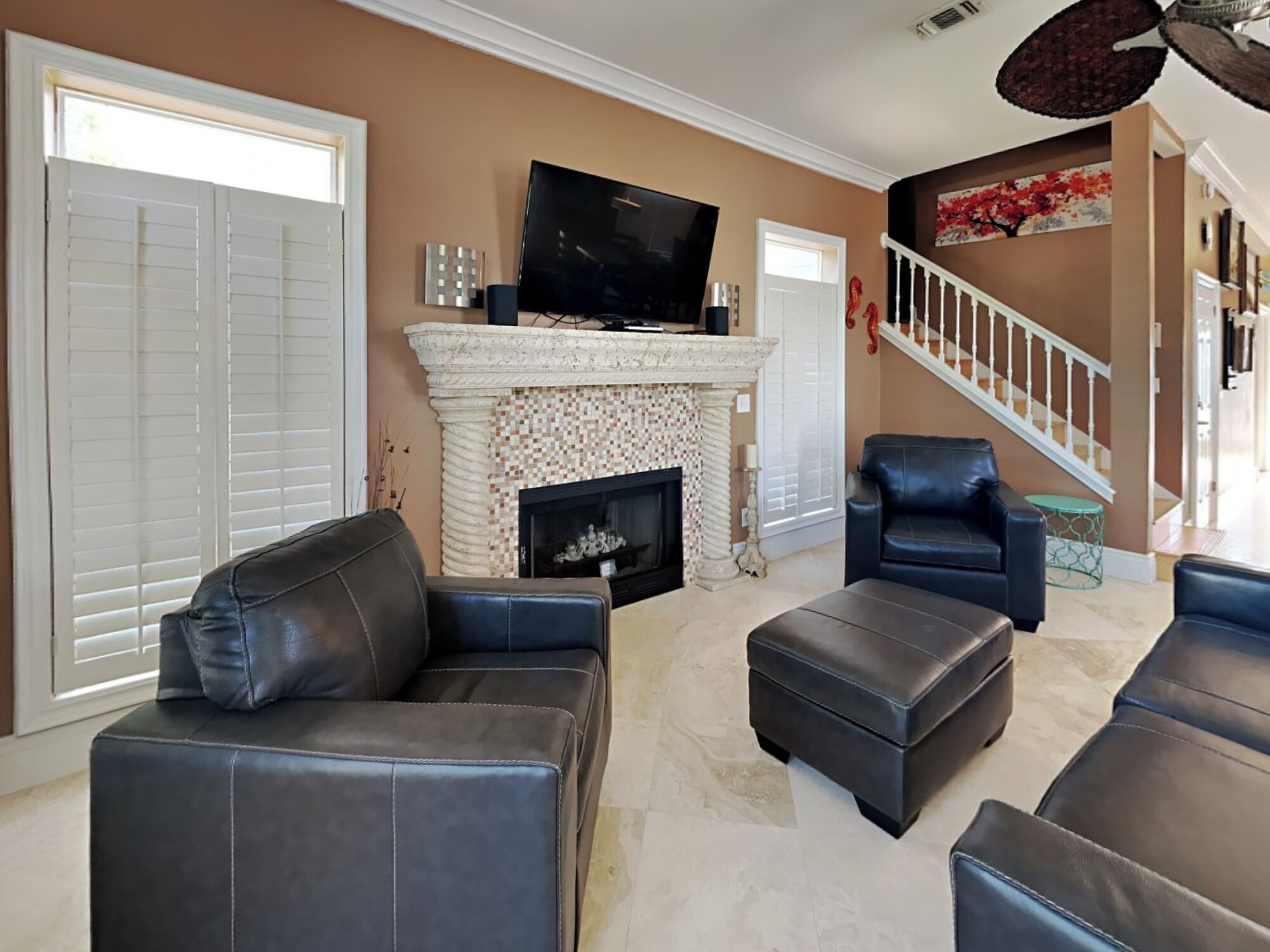 Una sala de estar con chimenea, televisión y muebles de cuero.