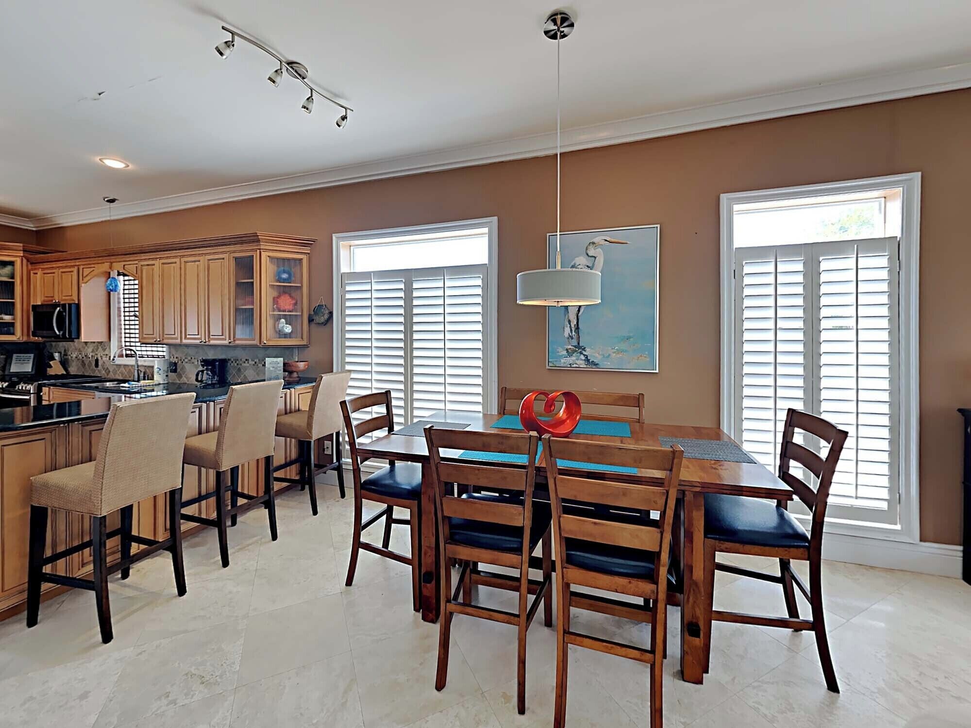 A spacious kitchen with wooden cabinets, a dining area with a large table and chairs, and a view through the windows.