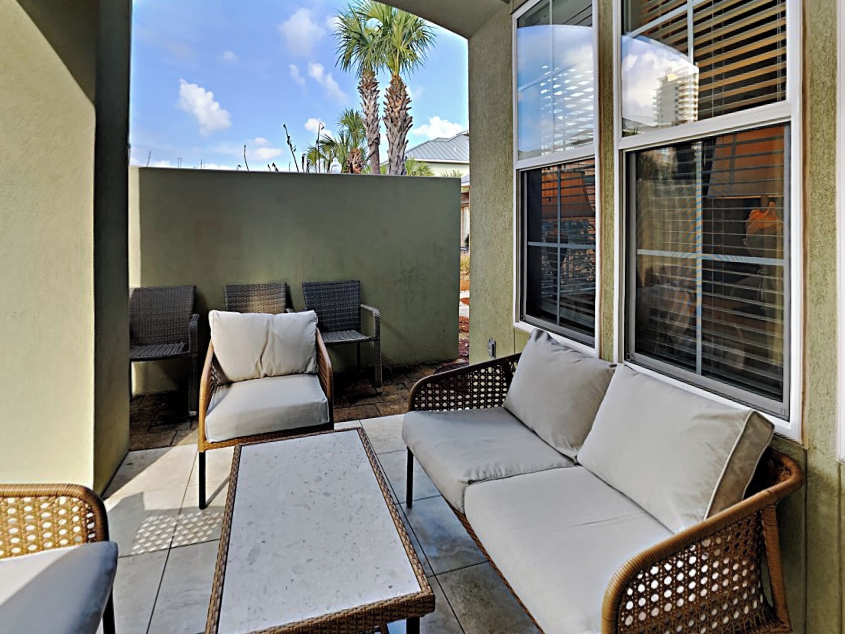 An outdoor patio area with wicker furniture, a white sofa, and a table.