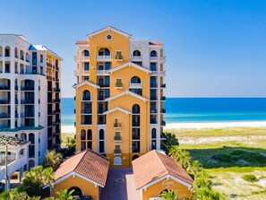 Un hotel de varios pisos con balcones, vista a la playa y un letrero que dice "Capri".