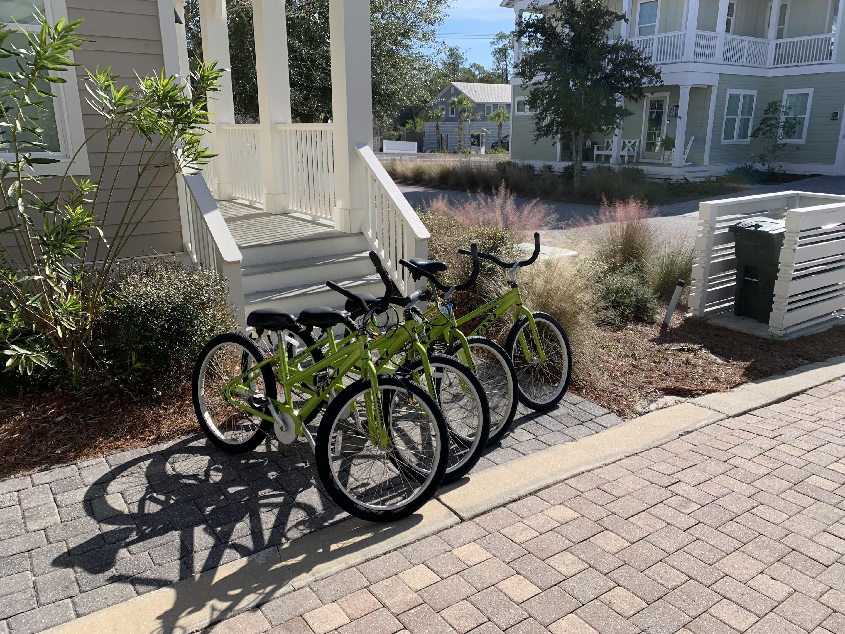 A row of bicycles parked on a paved area near a building with a white porch and steps.