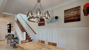 Ein Essbereich mit Holztisch und Stühlen, einer Chandelierleuchtre und einer Treppe, sowie einer Wand mit motivierenden Zitaten.