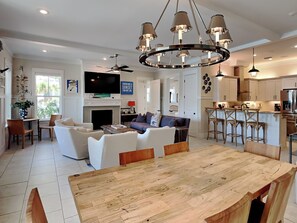 A modern living room with a wooden dining table, a sofa, and a TV mounted on the wall. - Sea La Vie In Grayton Beach by Southern Vacation Rentals (Santa Rosa Beach)