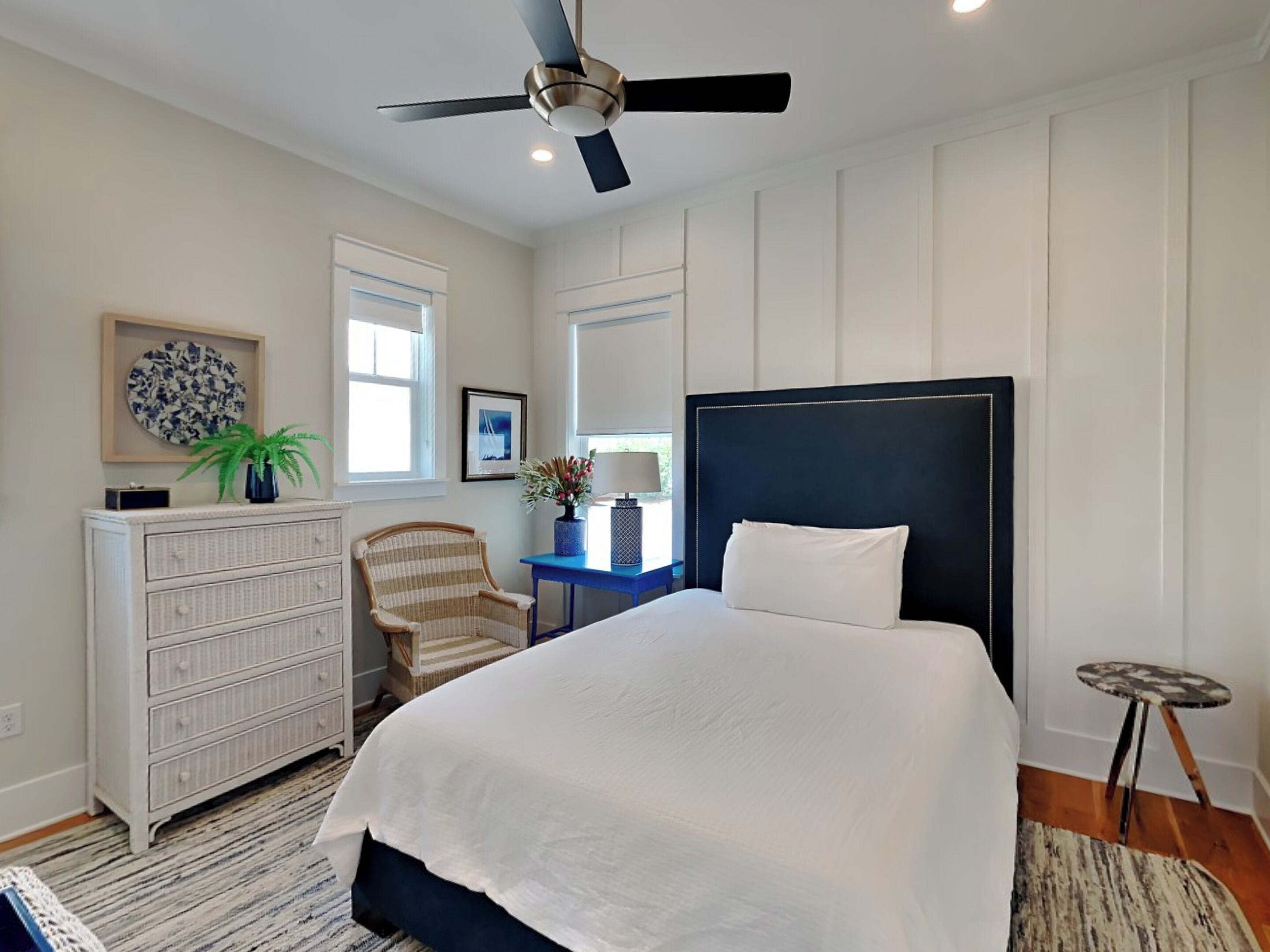A bedroom with a bed, dresser, chair, desk, and ceiling fan.