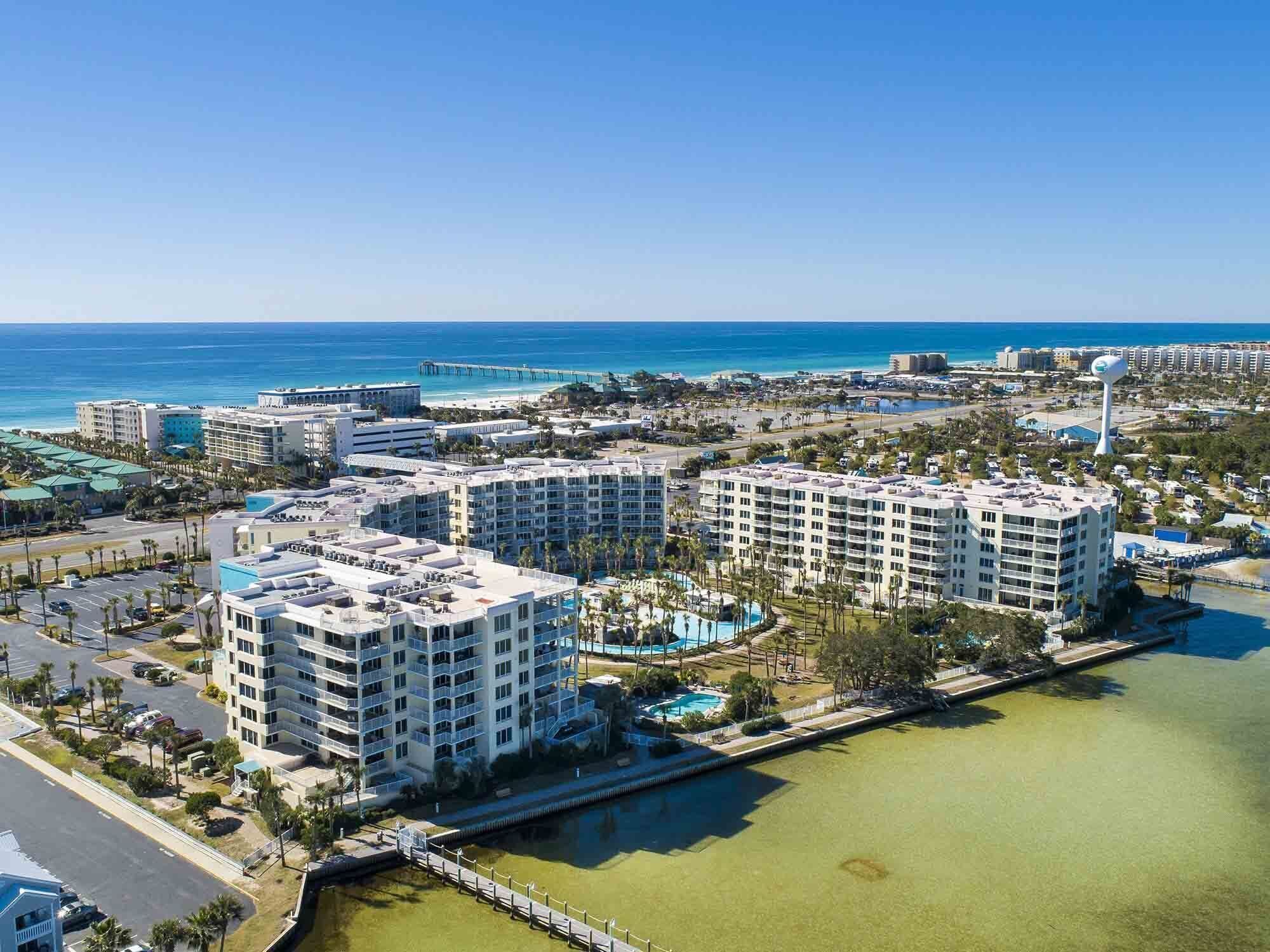 Un complejo hotelero frente al mar con varios edificios altos, un puerto deportivo y una vista despejada del océano.