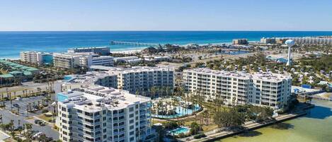 Un complejo hotelero frente al mar con varios edificios altos, un puerto deportivo y una vista despejada del océano.