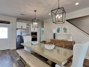 A modern kitchen with a large island, stainless steel appliances, and a dining area with wicker chairs and a glass table. - La Bella Luna by Southern Vacation Rentals (Navarre)