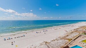 A beach with a clear sky, a swimming pool, and beach umbrellas. - Escapes to the Shores #704 by Southern Vacation Rentals (Orange Beach)