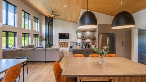 Una cocina moderna con comedor, ventanas amplias y techo de madera.
