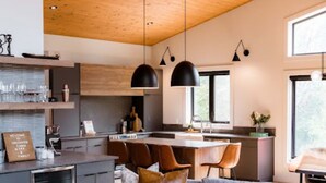 Una sala moderna con un sofá seccional gris, una mesa de centro de madera e iluminación colgante.