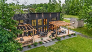 Een modern huis met een terras, zitplaatsen buiten en een pergola.