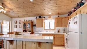 A spacious kitchen with wooden cabinets, a large island, and a refrigerator. - Walking Distance to Snow Summit (Big Bear Lake)