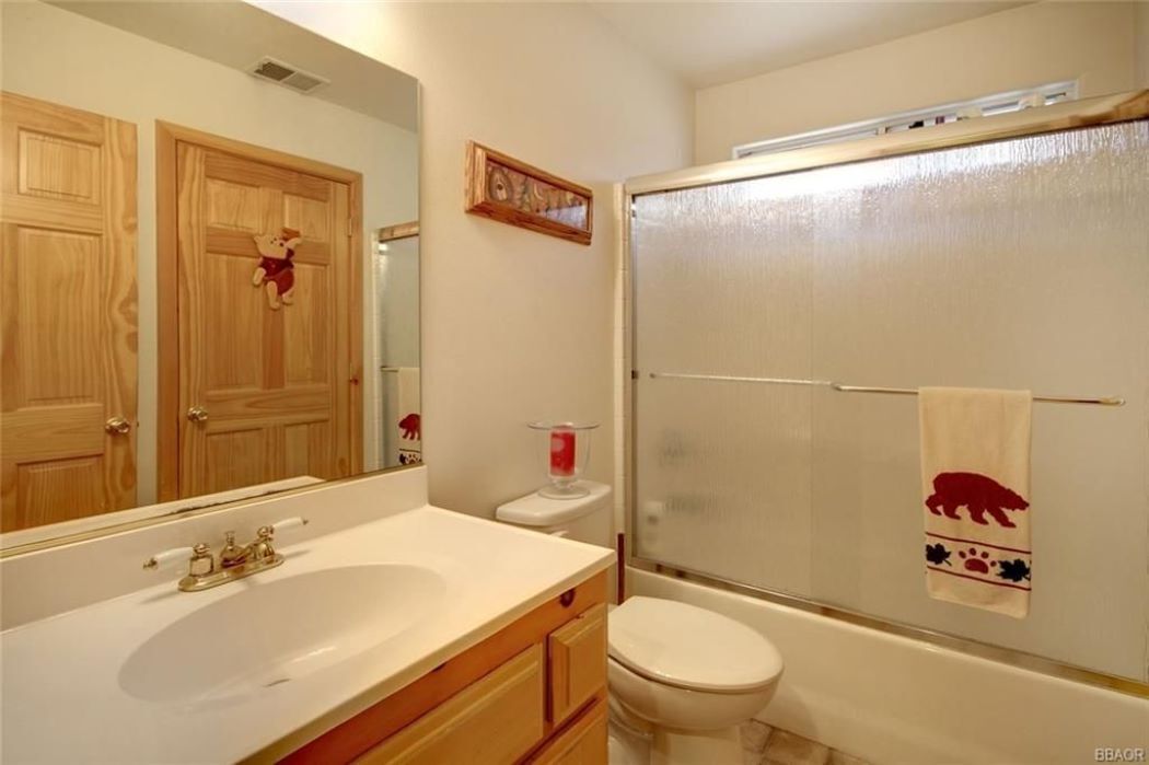 Un baño con tocador de madera, un espejo grande, inodoro y cabina de ducha de vidrio.