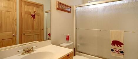 Un baño con tocador de madera, un espejo grande, inodoro y cabina de ducha de vidrio.
