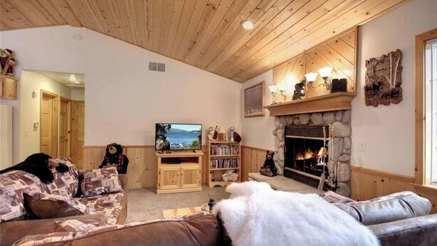 A cozy living room with a fireplace, wooden ceiling, and a television. - Walking Distance to Snow Summit (Big Bear Lake)