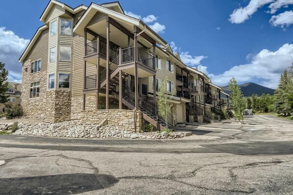 A multi-story building with balconies, stone facade, and a parking lot.