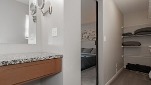 A bathroom with a granite countertop, a mirror with two smaller mirrors, and a shower area.