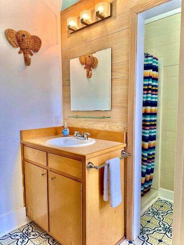 A bathroom with a wooden vanity, a mirror, a sink, and a shower curtain.