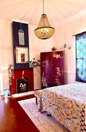 A bedroom with a bed, a fireplace, a wardrobe, and a hanging light fixture. - The Europe St Cottage (Baton Rouge)