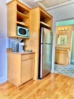 Una cocina con armarios de madera, un refrigerador de acero inoxidable, un microondas y una cafetera.