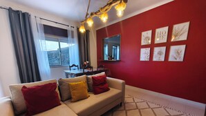 A living room with a sofa, red walls, and framed artwork. - Old Town & 10 min from Beach, Lagos (Lagos)