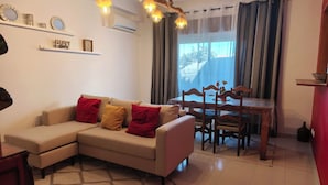 A living room with a sofa, a dining table with chairs, a chandelier, and a large window with curtains. - Old Town & 10 min from Beach, Lagos (Lagos)