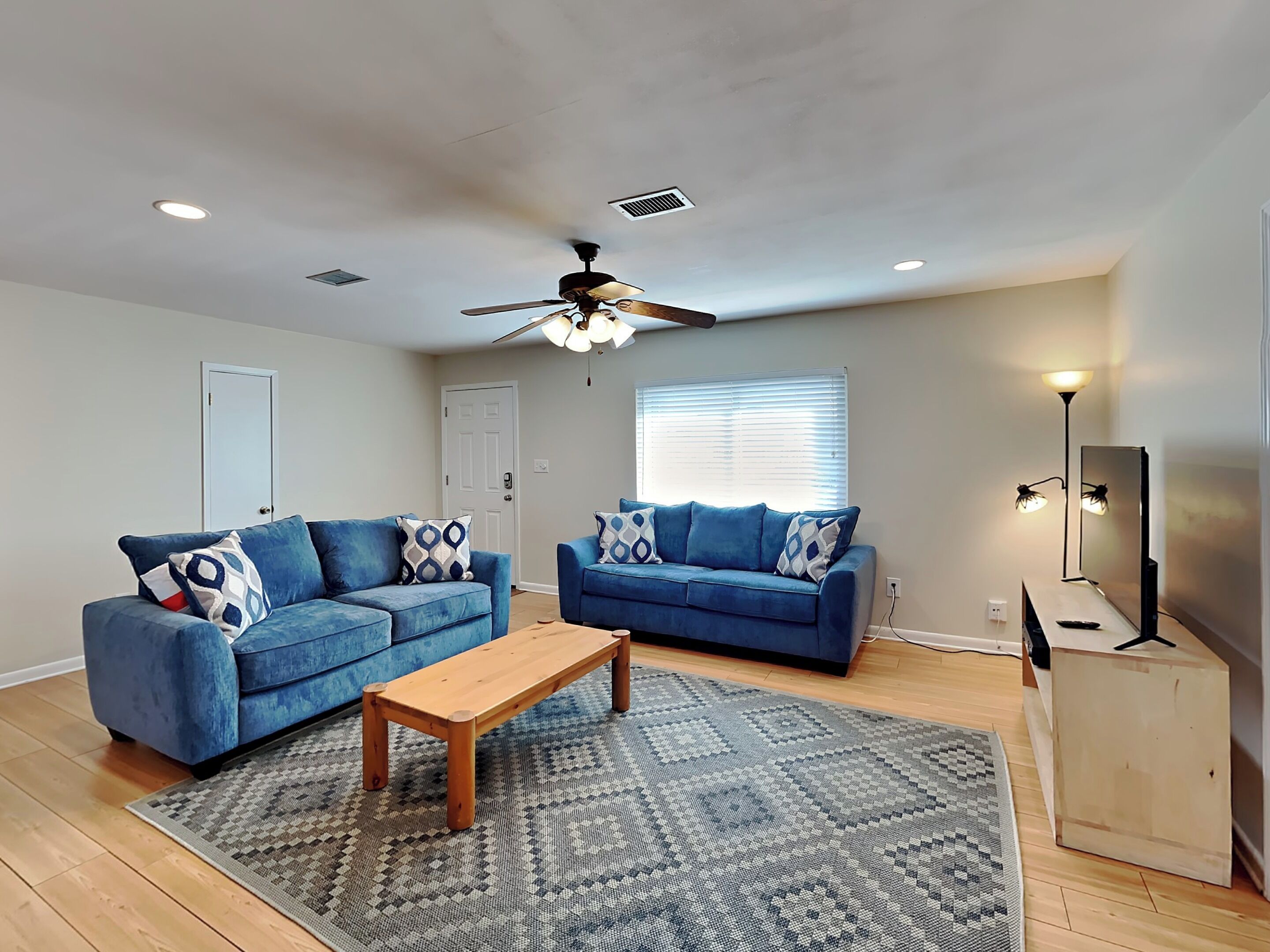 A living room with two blue sofas, a wooden coffee table, and a patterned rug.