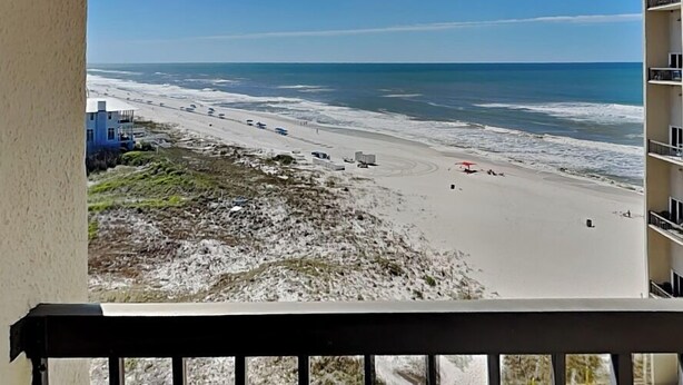 Une vue sur la plage depuis un balcon, avec un ciel dégagé.