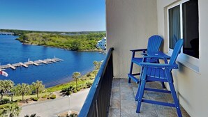 Un balcon avec deux chaises bleues, une vue sur un lac et une jetée.