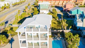 En høj bygning med altaner, swimmingpool og udsigt til stranden.