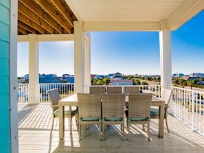 A covered outdoor patio with wicker furniture and a view of the surrounding area. - She Sells Seashells by Southern Vacation Rentals (Pensacola Beach)