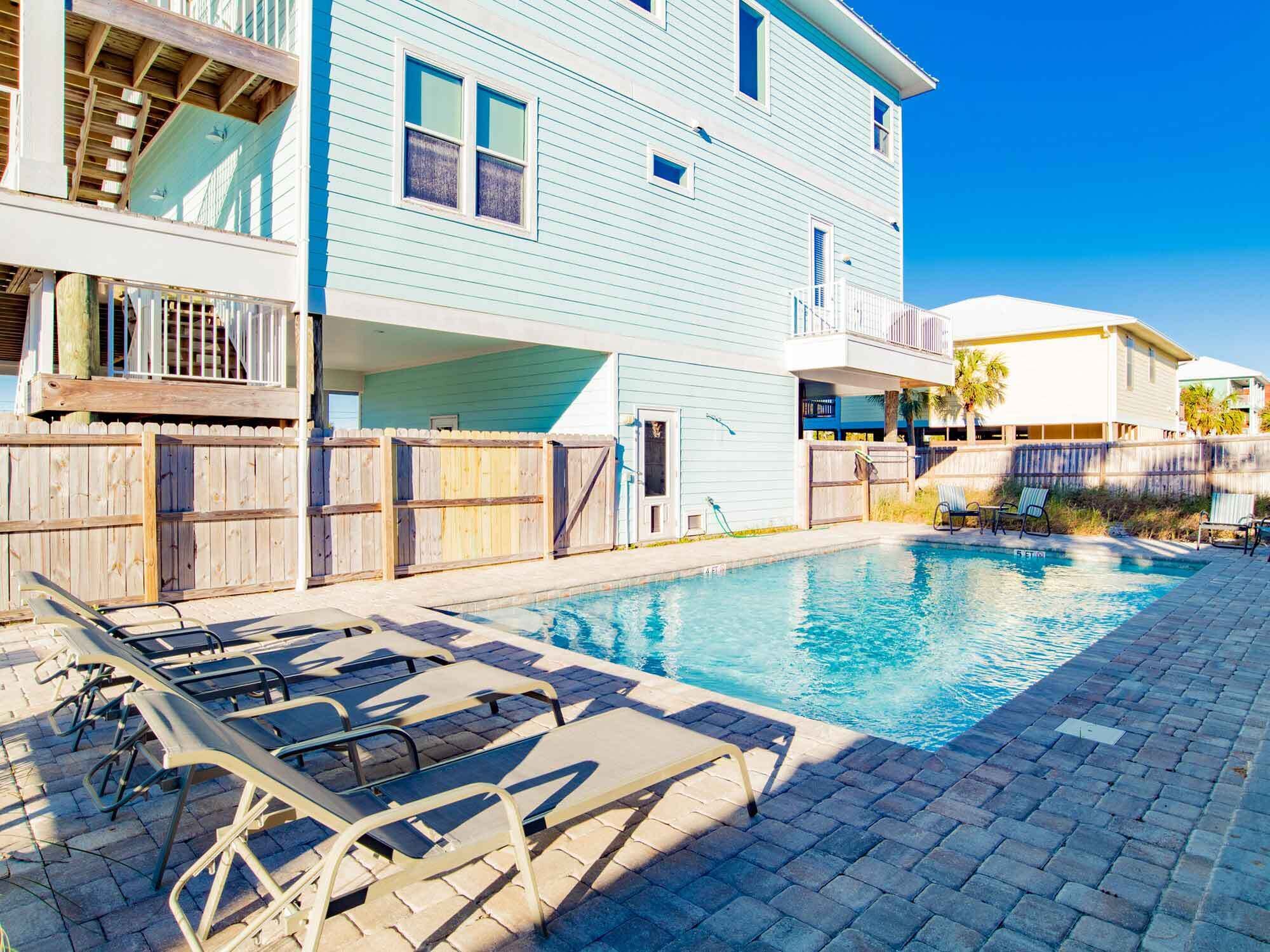 Edifício residencial com piscina, deck de madeira e espreguiçadeiras.