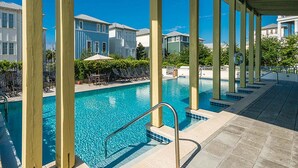 A pool area with clear blue water, lounge chairs, and a covered walkway. - Magnolia House by Southern Vacation Rentals (Santa Rosa Beach)