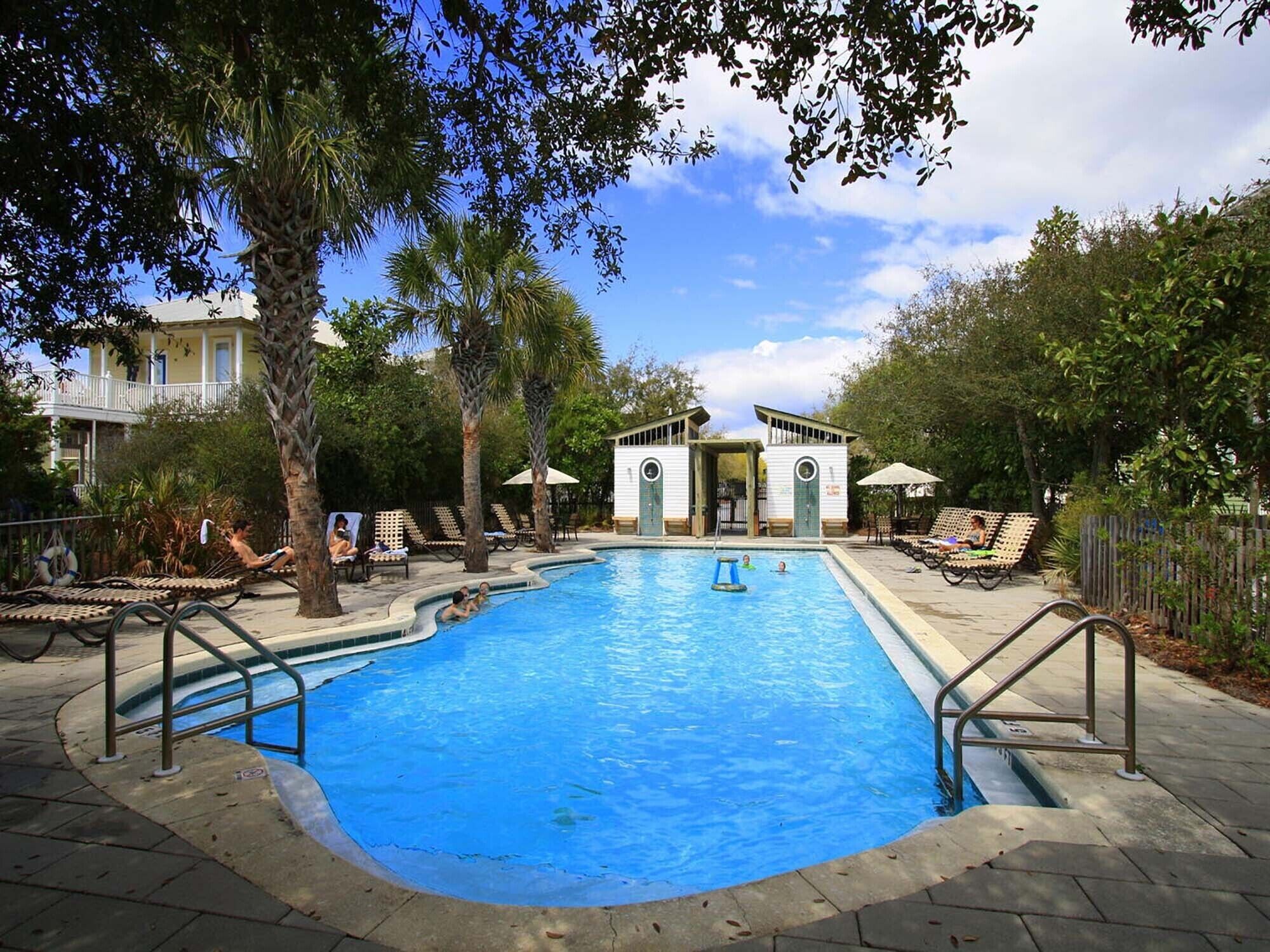 A swimming pool with lounge chairs and a small pavilion.