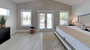 A bedroom with a large bed, two windows, a ceiling fan, and a small side table. - Happy as a Clam by Southern Vacation Rentals (Santa Rosa Beach)