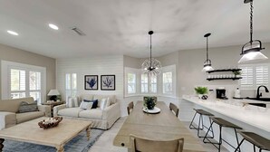 A modern kitchen with a central island, bar stools, and pendant lighting. - Happy as a Clam by Southern Vacation Rentals (Santa Rosa Beach)