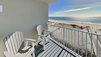 Un balcon avec deux fauteuils Adirondack donnant sur une plage.
