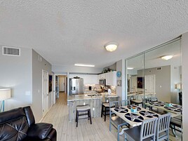 A modern kitchen with white cabinets, a stainless steel refrigerator, and a central island with bar stools.