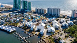 An aerial view of a coastal resort with multiple buildings, a marina, and a beach. - Cotton Bayou Condominiums by Southern Vacation Rentals (Orange Beach)