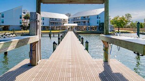 A wooden pier leading to a waterfront hotel with a covered walkway and multiple balconies. - Cotton Bayou Condominiums by Southern Vacation Rentals (Orange Beach)