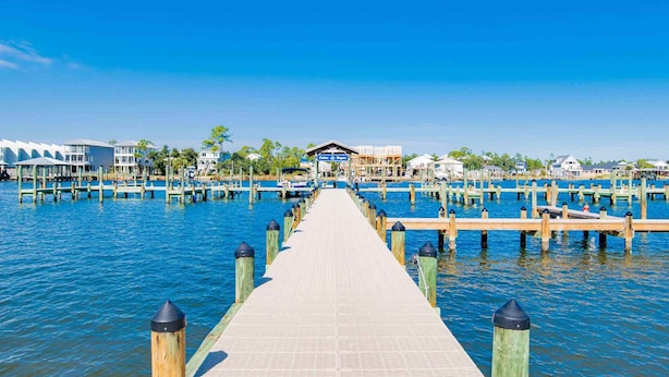 A wooden pier leading to a waterfront area with buildings and docks. - Cotton Bayou Condominiums by Southern Vacation Rentals (Orange Beach)