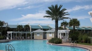 A swimming pool with a brick deck, palm trees, and covered seating areas. - Sunny Days by Southern Vacation Rentals (Miramar Beach)