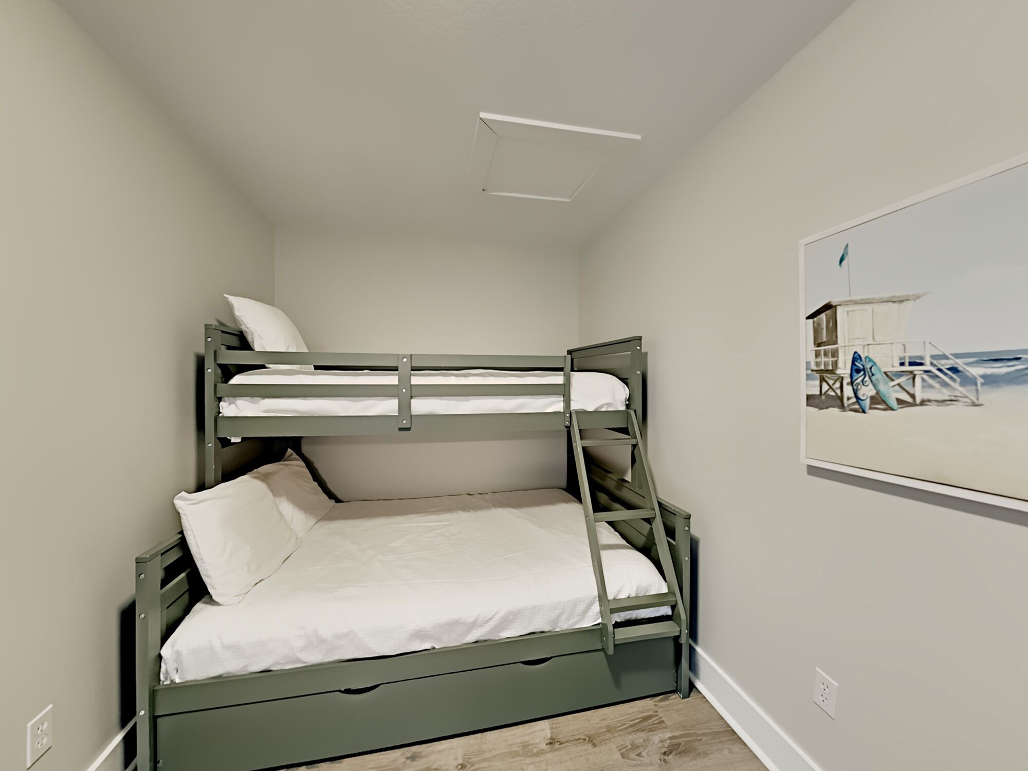 A bunk bed room with a beach scene painting on the wall.
