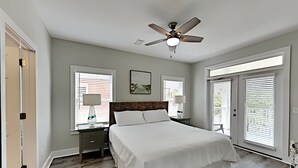 A bedroom with a large bed, two bedside tables, a ceiling fan, and a window with blinds. - Sunny Days by Southern Vacation Rentals (Miramar Beach)