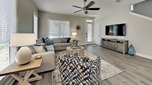 A modern living room with a sectional sofa, a coffee table, and a television. - Sunny Days by Southern Vacation Rentals (Miramar Beach)